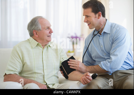 USA,New Jersey,Jersey City,Smiling man taking senior man's blood pressure Stock Photo