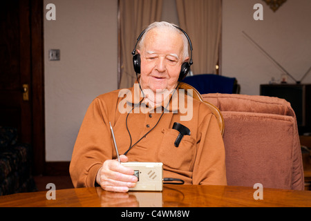 A retired elderly Senior Man listening to radio with headphones. Stock Photo