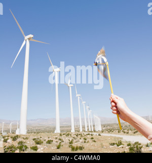 USA,California,Palm Springs,Coachella Valley,San Gorgonio Pass,Woman's hand holding pinwheel against blue sky and wind turbines Stock Photo