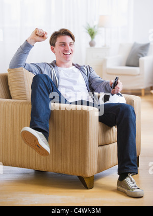 USA,New Jersey,Jersey City,man sitting in chair and watching TV soccer game Stock Photo