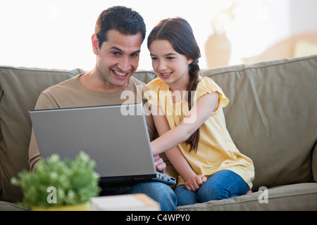 USA,New Jersey,Jersey City,daughter (8-9) and father sitting on sofa and using laptop Stock Photo