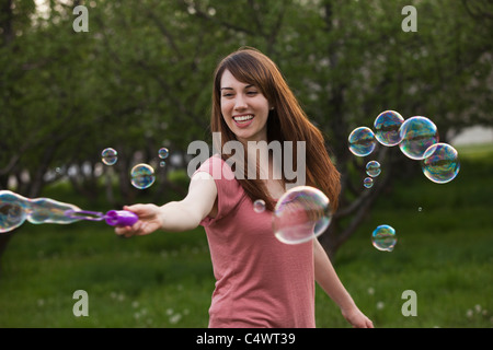 USA,Utah,Provo,Young woman blowing bubbles in orchard