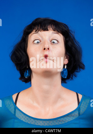 middle-aged woman making funny faces - isolated on blue Stock Photo