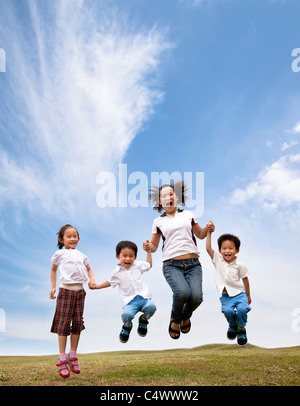 happy asian family jumping on the grass field. mother and her children