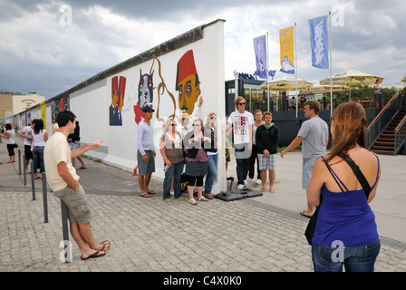 Young tourists photographing graffitis at Eastside Gallery, remaining part of former Berlin Wall, renovated 2009. Berlin. Stock Photo