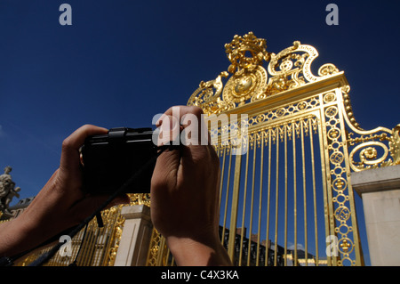 The hands of a photographer taking a picture of the golden gate at the Chateau of Versailles near Paris Stock Photo