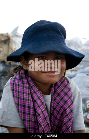 A young child laborer girl living in poverty is searching through garbage at a polluted garbage dump in Cambodia. Stock Photo