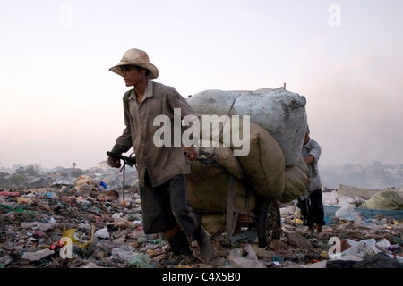 Workers are transporting garbage sacks at a toxic and polluted trash dump in Cambodia. Stock Photo