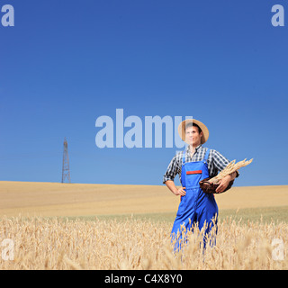 A young farmer with panama hat holding a basket in a field Stock Photo