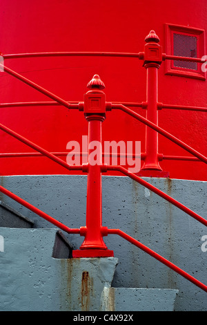 Abstract architectural detail photo of a set of concrete stairs with bright red railings against a bright red wall. Stock Photo