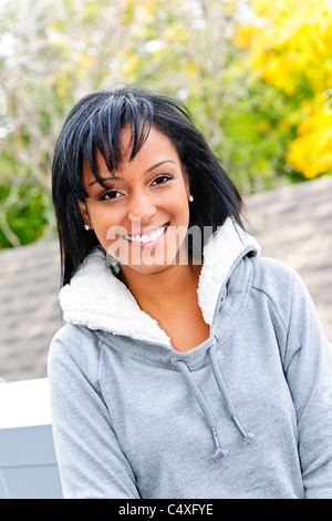 Portrait of happy smiling young black woman outside in the fall Stock Photo