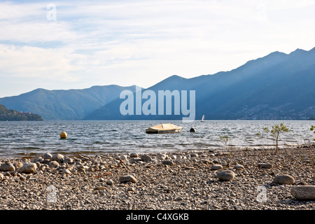 a boat on Lake Maggiore with a beach in the foreground Stock Photo