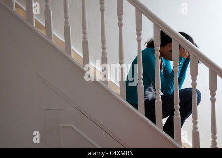 Young woman sitting alone on stairs hands on head. Stock Photo