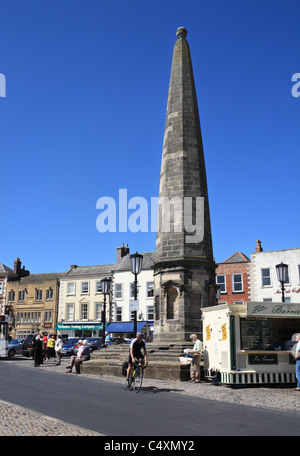 A man cycles past the obelisk in Richmond market place, North Yorkshire, England, UK Stock Photo
