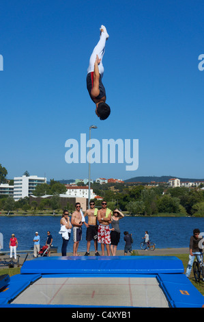 Male gymnast jumping off trampoline in the air against a blue sky Stock Photo