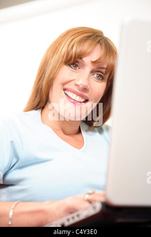Woman using a laptop computer, smiling. Stock Photo