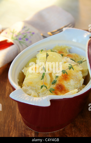 Potato gratin dauphinoise in the pan on rustic background Stock Photo
