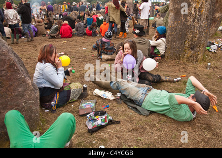 Couple breathing in balloons of nitrous oxide - laughing gas at the stone circle in Kings Meadow, Glastonbury Festival 2011 Stock Photo