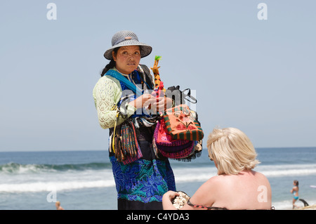 A woman beach vendor shows her merchandise to a tourist on the beach in Sayulita, Nayarit, Mexico. Stock Photo