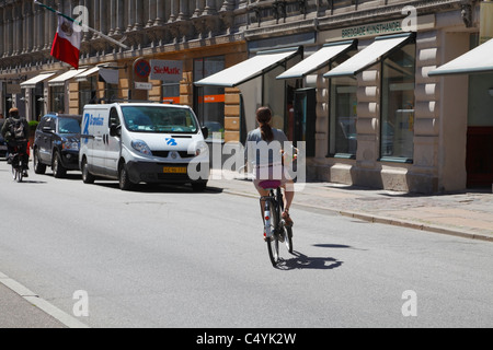Young female cyclist entering Bredgade in the city of Copenhagen one hot summer afternoon. Copenhagen, Denmark. Stock Photo