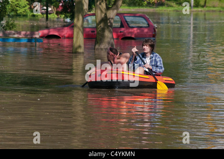 Men in pontoon paddling across flooded parking lot near apartment building, 2010 flood at Kozanow area of Wrocław, Poland Stock Photo