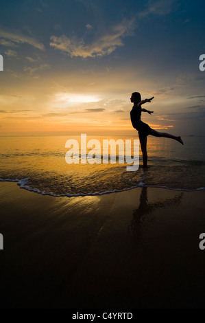 A young woman doing yoga exercises on the beach at sunset.Taken on Phra Ae Beach (Long Beach), Koh Lanta (Lanta Island),Thailand