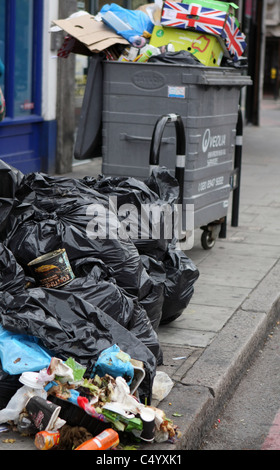 Rubbish in wheelie bin and in black sacks in a street in London Stock Photo