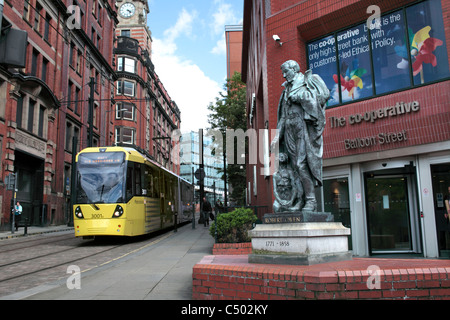 A tram passing a statue of Robert Owen outside the Co-op Bank on Balloon Street, Manchester. Stock Photo