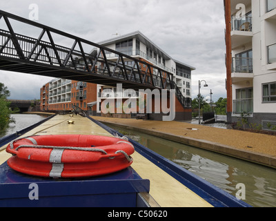 A narrow boat passing through an urban landscape on the Grand Union Canal at Wolverton, Buckinghamshire, England. Stock Photo