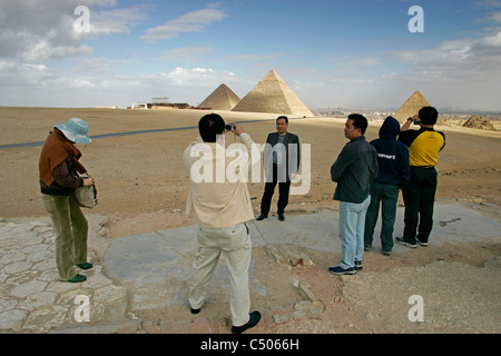 Tourists pose for and take photographs with the Great Pyramids of Giza as a backdrop. Cairo, Egypt. Stock Photo