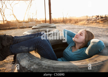 Caucasian teenager sitting in large tire Stock Photo