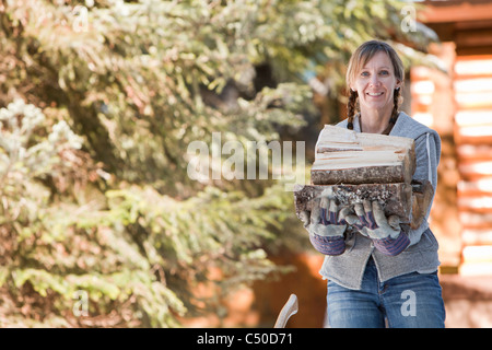 Caucasian woman carrying firewood Stock Photo