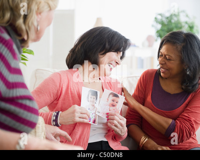 Woman showing friends photographs of her grandchildren Stock Photo