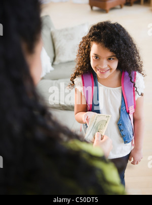 Mother handing money to daughter Stock Photo