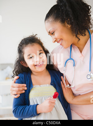 Smiling nurse giving girl lollipop Stock Photo