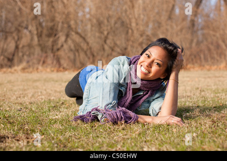Smiling Asian woman laying in grass Stock Photo