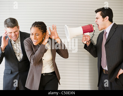 Businessman shouting through bullhorn at co-workers Stock Photo