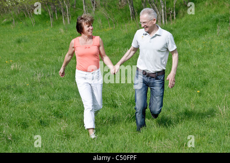 Middle-aged couple walking hand in hand in a meadow Stock Photo