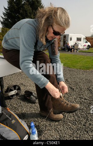 Female walker tying up her laces on a campsite  before setting off for a walk  near Bellingham, Northumberland, England, UK Stock Photo