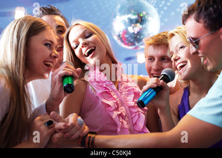 Portrait of joyous guys and girls singing at party together Stock Photo