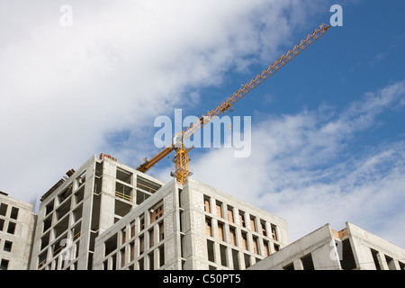 Yellow construction crane, an unfinished concrete house on the skyline Stock Photo