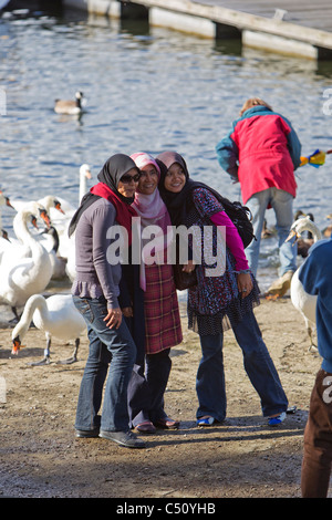 Female , girls  having a group photograph taken ,with swans and Bowness Bay behind Stock Photo