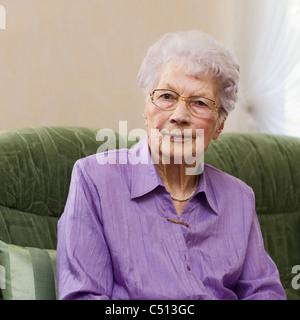 91 years old woman sitting on couch in her living room, portrait Stock Photo