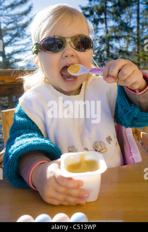 Baby girl eating yogurt with spoon Stock Photo