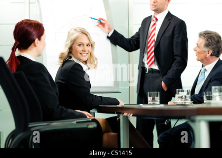 Business - presentation within a team; a colleague is standing on the flipchart Stock Photo