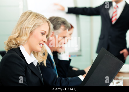 Business - presentation within a team; a colleague is standing on the flipchart Stock Photo