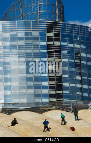 Workers standing on roof examining office building Stock Photo
