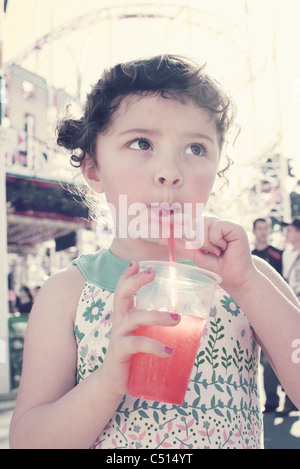 Little girl drinking juice at fair Stock Photo