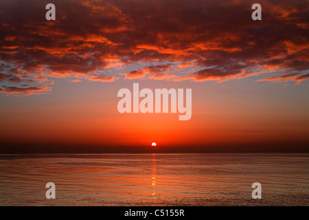 A layer of clouds is lit by the rising sun over Rio de la Plata, Buenos Aires, Argentina. Stock Photo