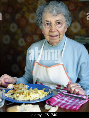 Senior woman eating at table, portrait